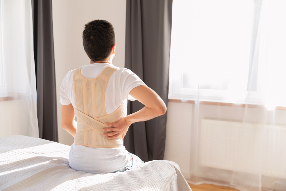 Man with back brace in bed